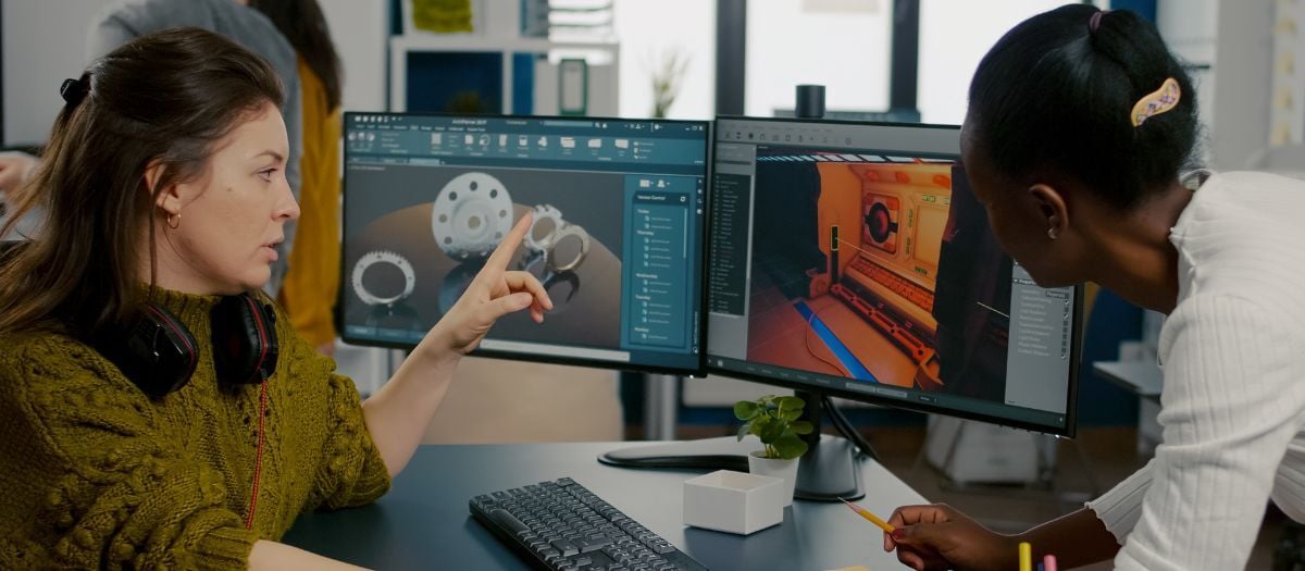 Female engineers collaborate on a 3D mechanical model using Autodesk CAD software.